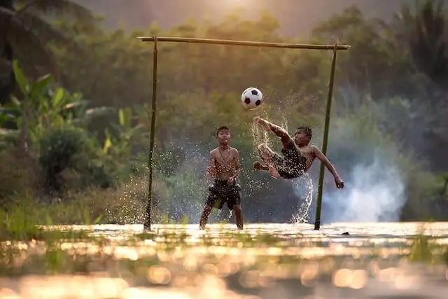 two kids playing soccer on a rainy day