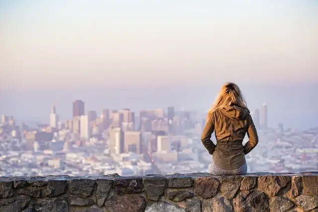 woman on a rock watching a city