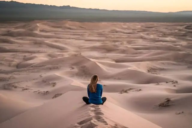 woman sitting on sand field during daytime