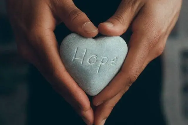 person holding stone on which it says hope