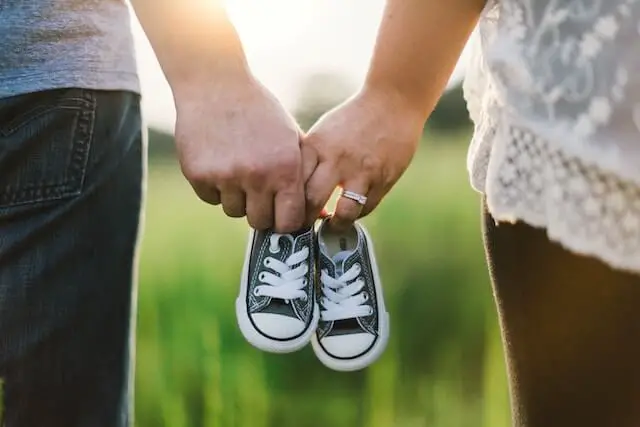 woman and man holding baby shoes