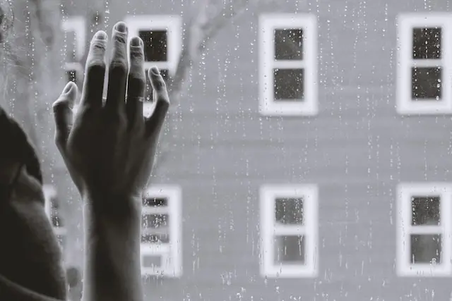 woman hand on rainy glass
