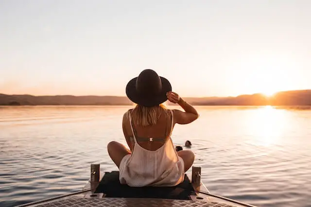 woman sitting on a lake pier
